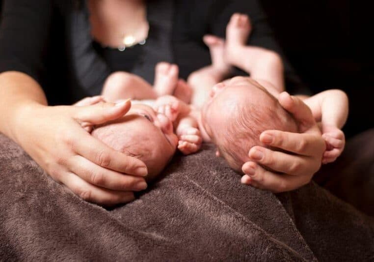 new mom holding twins postpartum on lap