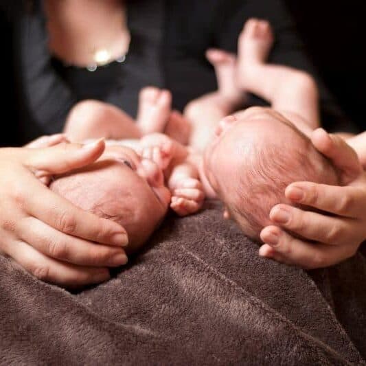 new mom holding twins postpartum on lap