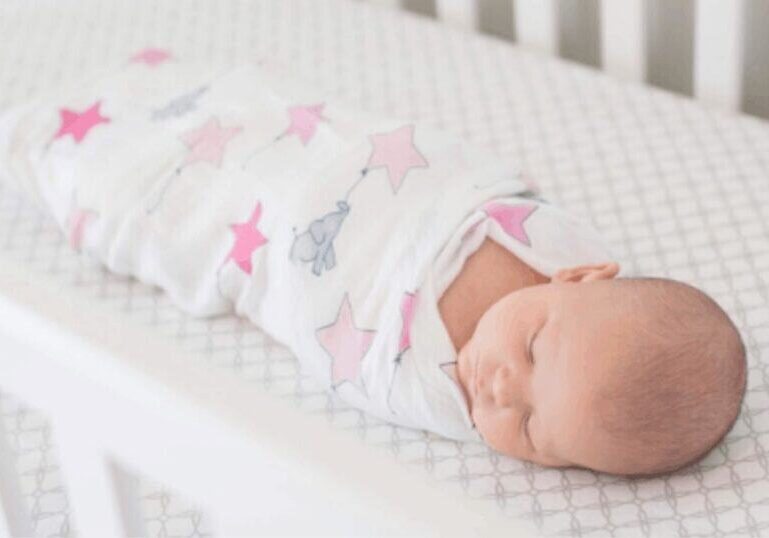 sleeping baby swaddled in crib