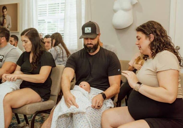 Pregnant couple practice swaddling at Tampa FL newborn care class with Buddha Belly Doulas