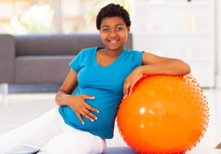 pregnant woman leaning on yoga ball